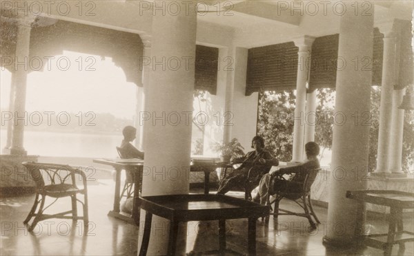 Relaxing on the veranda near Calcutta. Three British women relax in cane chairs on the veranda of a bungalow overlooking the Hooghly River. Near Calcutta (Kolkata), India, December 1930. Kolkata, West Bengal, India, Southern Asia, Asia.
