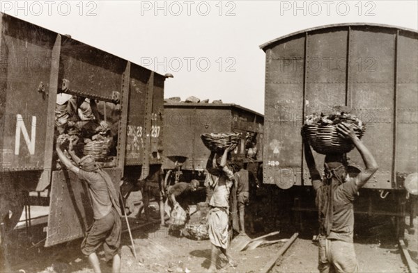 Coaling, the old fashioned way'. Indian porters collect baskets of coal from a railway freight car before carrying their loads away to fuel ships moored at Calcutta docks. Calcutta (Kolkata), India, 1931. Kolkata, West Bengal, India, Southern Asia, Asia.