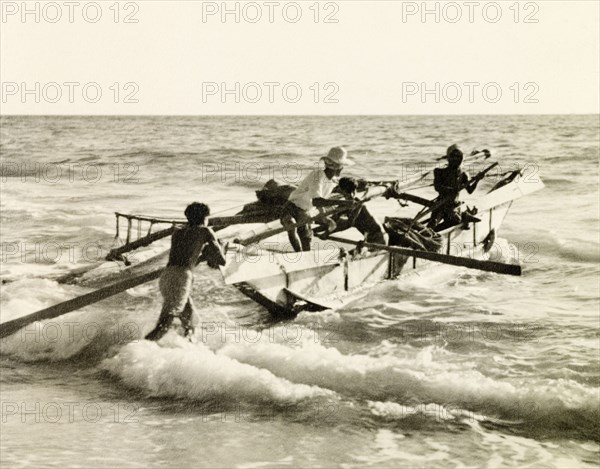Launching a fishing boat, Puri. Four fishermen launch their fishing boat into the surf at Puri beach. Puri, India, October 1934. Puri, Orissa, India, Southern Asia, Asia.