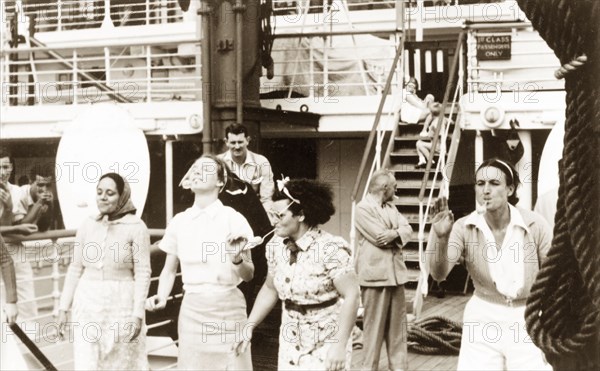 Egg and spoon race aboard the Otranto. Four women compete in an egg and spoon race, holding the spoons in their mouths on the deck of the 'Otranto', a passenger liner belonging to the Orient Line. The ship was travelling from Colombo in Ceylon (Sri Lanka) to Plymouth in England. Indian Ocean, February 1939., Indian Ocean, Africa.