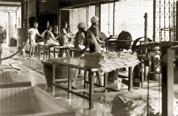 Interior of a rubber factory, British Malaya. Factory workers operate machinery to produce sheets of latex at a rubber factory. Perak, British Malaya (Malaysia), September 1940., Perak, Malaysia, South East Asia, Asia.