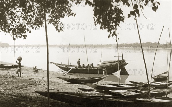 Unloading cargo on the Hooghly River. Men unload cargo from a small boat moored in the shallows of the Hooghly River. Bengal (West Bengal), India, October 1940., West Bengal, India, Southern Asia, Asia.