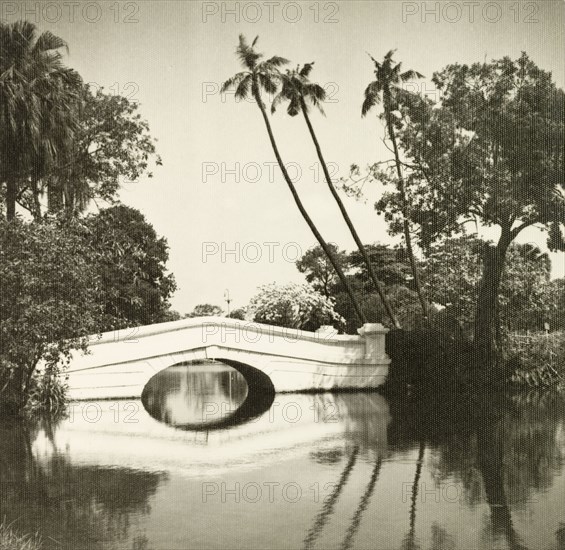 Eden Gardens, Calcutta. A stone footbridge spans a tranquil pool in Eden Gardens. Calcutta (Kolkata), India, November 1940. Kolkata, West Bengal, India, Southern Asia, Asia.