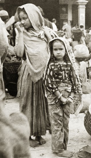 At Darjeeling market. A girls stand in a marketplace in Darjeeling. Both wear traditional dress including a 'dupatta' (headscarf), which covers their heads and shoulders. Darjeeling, India, 1942. Darjeeling, West Bengal, India, Southern Asia, Asia.