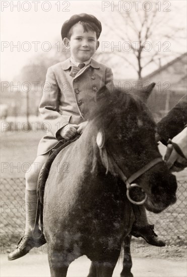 Pony ride at the zoo. A British boy named Tim smiles for the camera as he rides a pony during a trip to the zoo. England, 1951. England (United Kingdom), Western Europe, Europe .