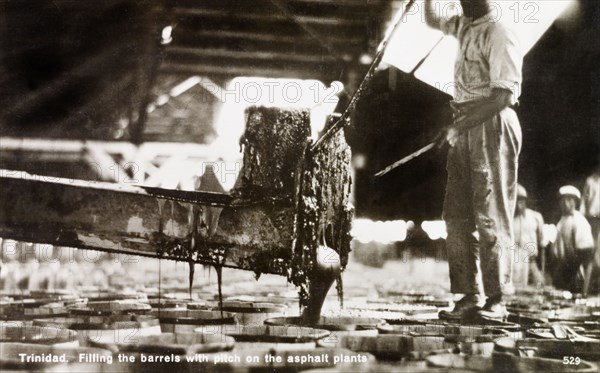 Asphalt manufacturing plant. A factory worker pours liquid asphalt taken from the Pitch Lake at La Brea into a series of barrels at a manufacturing plant. Trinidad, circa 1930., Trinidad and Tobago, Trinidad and Tobago, Caribbean, North America .