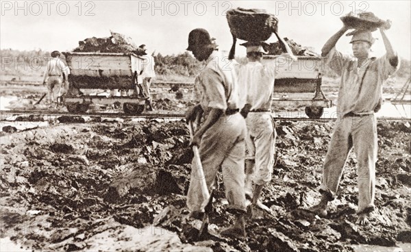 Extracting asphalt from the Pitch Lake. Labourers dig lumps of asphalt from the Pitch Lake and load it into a waiting rail car. Trinidad, circa 1938. La Brea, Trinidad and Tobago, Trinidad and Tobago, Caribbean, North America .