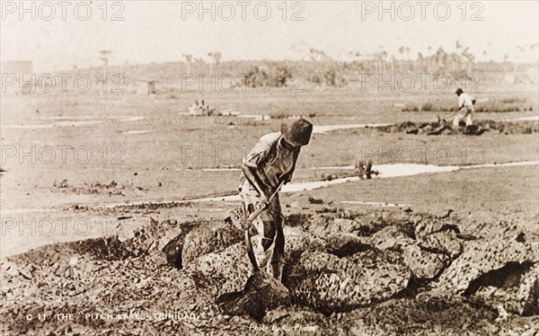 Extracting asphalt from the Pitch Lake. A labourer uses a pickaxe to extract lumps of asphalt from the Pitch Lake, a natural asphalt lake located on Trinidad's west coast. La Brea, Trinidad, circa 1933. La Brea, Trinidad and Tobago, Trinidad and Tobago, Caribbean, North America .