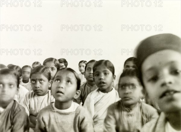 Indian schoolchildren. A class of Indian schoolchildren sit on the floor and listen attentively to an unseen speaker at a Methodist missionary school. Tumkur (Tumakuru), Karnataka, India, circa 1932., Karnataka, India, Southern Asia, Asia.