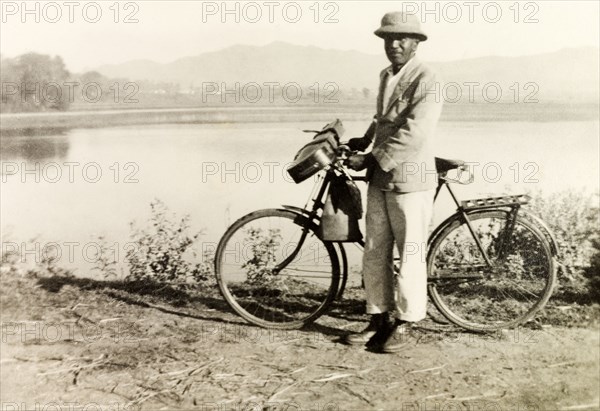 Mr Arthur, a Methodist evangelist. Portrait of Mr Arthur, a Methodist evangelist, standing with his bicycle beside a picturesque lake in the foothills of the Baba Budan Giri mountain range. Chikmagalur, Mysore State (Chikkamagaluru, Karnataka), India, circa 1936., Karnataka, India, Southern Asia, Asia.