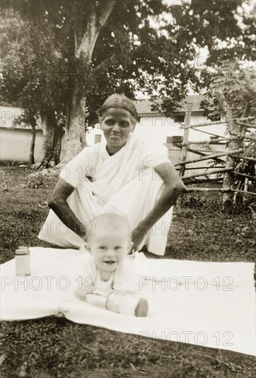Indian ayah with baby Nell. An Indian ayah (nursemaid) watches over a six month old baby, Nell Sargant, as she plays on a rug in the garden. Chikmagalur, Mysore State (Chikkamagaluru, Karnataka), India, June 1937., Karnataka, India, Southern Asia, Asia.