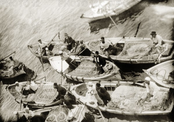 Rug vendors, Port Said. Egyptian rug vendors vie for trade in canoes at Port Said harbour. Port Said, Egypt, 1931. Port Said, Port Said, Egypt, Northern Africa, Africa.