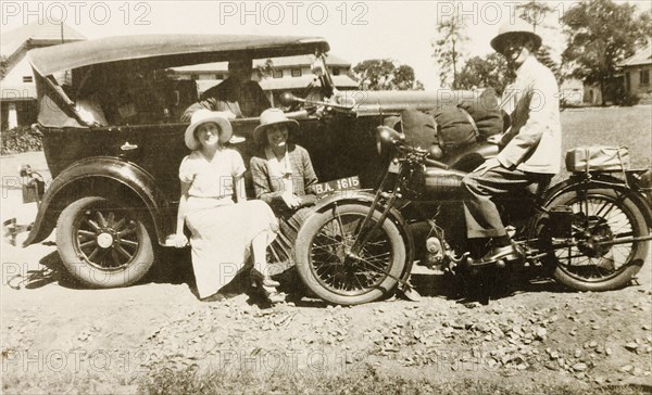 Socialising at the United Theological College. British colonists Netta Spence and Constance Boote pose on the fender of a motor car in the grounds of the United Theological College. They are chatting with two European men: one of whom sits in the car's driver seat, the other on the back of a motorcycle. Bangalore, Karnataka, India, circa 1932. Bangalore, Karnataka, India, Southern Asia, Asia.