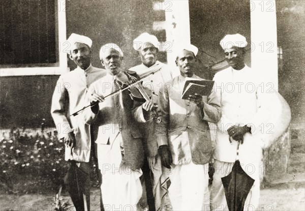 A Methodist evangelist band. Group portrait of a Methodist evangelist band, who sing a song from a hymn book to the accompaniment of a violin. Tumkur, Mysore State (Tumakuru, Karnataka), India, circa 1933., Karnataka, India, Southern Asia, Asia.