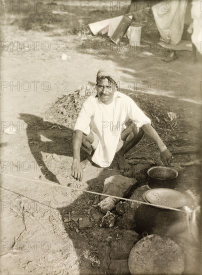 Cooking food at a Methodist camp site. A Methodist evangelist called Markappa cooks food over a smoky camp fire. Markappa was accompanying British missionary Reverend Norman Sargant, who travelled throughout Mysore State preaching to rural Christian communities. Mysore State (Karnataka), India, 1933., Karnataka, India, Southern Asia, Asia.