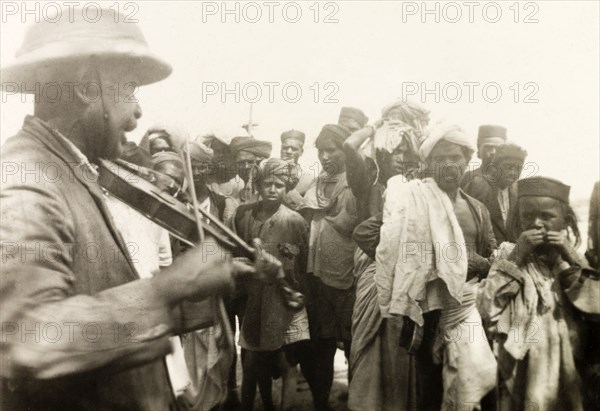 Methodist missionary playing violin. Mr A.C. Arthur, a Methodist evangelist, plays a violin to a crowd of Indian plantation workers. Mr Arthur was accompanying British missionary Reverend Norman Sargant, who travelled throughout Mysore State preaching to rural Christian communities. Mysore State (Karnataka), India, 1934., Karnataka, India, Southern Asia, Asia.