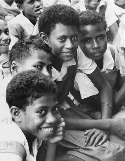 Fijian girls in uniform. Originally captioned "a mother with her small family", this portrait appears to feature four girls of a similar age, possibly schoolchildren, all dressed in uniform comprising blouses and pinafore dresses. Fiji, 1965. Fiji, Pacific Ocean, Oceania.