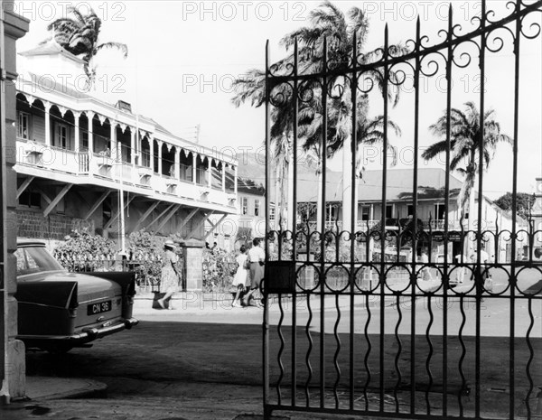 Gate onto the main square, Basseterre. An ornate iron gate belonging to government buildings opens out onto the main square in Basseterre. Basseterre, St Kitts, 1965. Basseterre, St George Basseterre, St Kitts and Nevis, Caribbean, North America .
