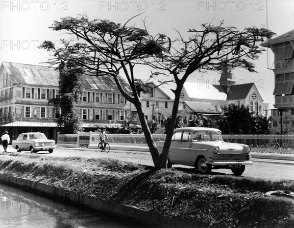 Main street of Georgetown, British Guiana. The main street of Georgetown, featuring a canal in the foreground and colonial style buildings in the distance. Georgetown, British Guiana (Guyana), 1965. Georgetown, Demerara-Mahaica, Guyana, South America, South America .