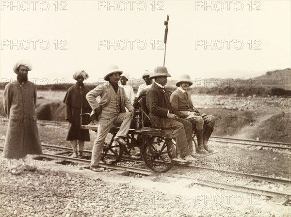 Rail cart on Kohat-Thal railway line. Three European men sit on a hand-operated rail cart on the Kohat-Thal railway line, attended to by four Indian servants and railway workers. North West Frontier Province, India (Pakistan), February 1903., North West Frontier Province, Pakistan, Southern Asia, Asia.