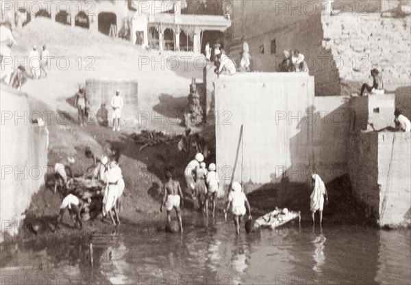 A cremation ghat in Benares. Mourning Hindus prepare to perform a cremation at a ghat (stepped wharf) on the River Ganges. Benares, United Provinces (Varanasi, Uttar Pradesh), India, December 1902. Varanasi, Uttar Pradesh, India, Southern Asia, Asia.