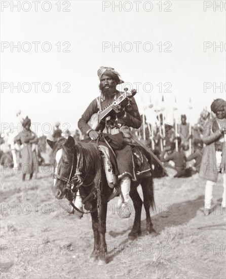 Musician at Coronation Durbar, 1903. A mounted chief from Haripur State plays a traditional Indian stringed instrument (similar to a sarod or sitar) at the Coronation Durbar. Delhi, India, circa 1 January 1903. Delhi, Delhi, India, Southern Asia, Asia.