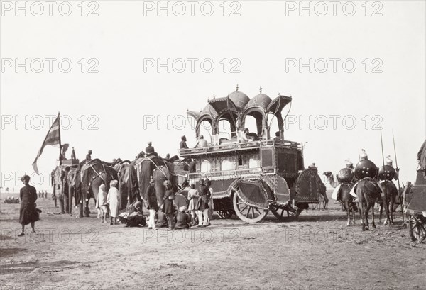 Alwar State procession at Coronation Durbar, 1903. A team of caparisoned elephants pull Alwar State's large, ceremonial carriage at the Coronation Durbar. The ornate vehicle has two storeys: the enclosed lower section for female passengers and the open upper level for men. Delhi, India, circa 1 January 1903. Delhi, Delhi, India, Southern Asia, Asia.