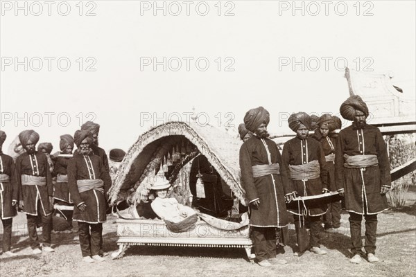 Silver palanquin at Coronation Durbar, 1903. A European lady travels in an ornate silver palanquin carried by a team of uniformed Indian bearers during a procession at the Coronation Durbar. Delhi, India, circa 1 January 1903. Delhi, Delhi, India, Southern Asia, Asia.