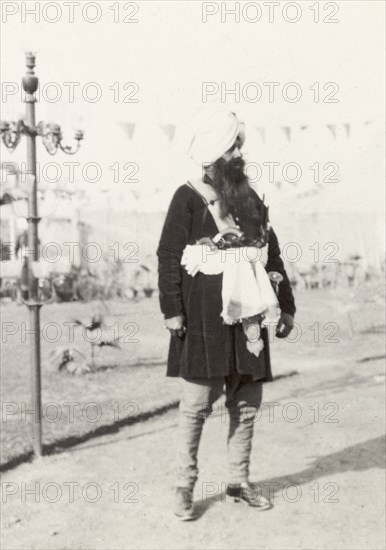 Royal Sikh guest at Coronation Durbar, 1903. Full-length portait of a royal Sikh guest at Edward VII's Coronation Durbar. He sports a long beard and is dressed in traditional clothing, including a turban, a 'dhoti' and a 'sherwani' (coat), over which he wears a cloth holster in which he keeps his 'kirpan' (Sikh ceremonial dagger). Delhi, India, circa 1 January 1903. Delhi, Delhi, India, Southern Asia, Asia.