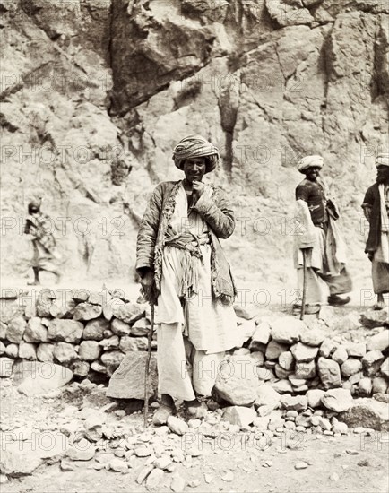 A Pashtun man on the Khyber Pass. Portrait of a turbaned Pashtun man posing by a dry stone wall on the Khyber Pass. North West Frontier Province, India (Pakistan), 1903. Pakistan, Southern Asia, Asia.