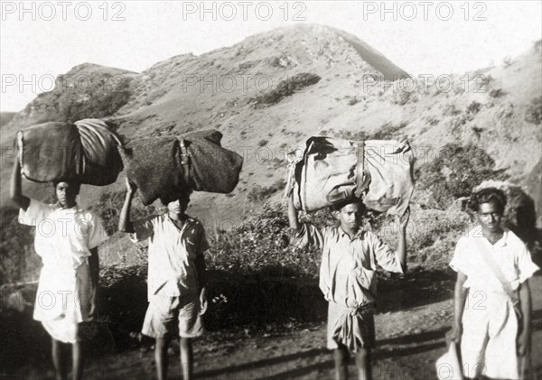 Indian porters in the Baba Budan Giri mountains. A team of Indian porters balance large bundles on their heads as they trek through the Baba Budan Giri mountain range. Mysore State (Karnataka), India, circa 1936., Karnataka, India, Southern Asia, Asia.