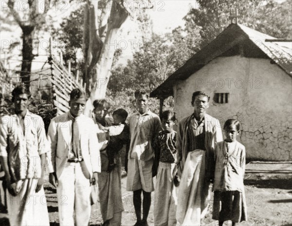 Evangelists visiting plantation workers, India. Two Methodist evangelists, J.A. Dennis and Monahan Peter (both standing far left), pose with plantation workers at the 'Maskal Maradi' coffee estate, whilst on a visit with British missionary Reverend Norman Sargant. Chikmagalur, Mysore State (Chikkamagaluru, Karnataka), India, circa 1936., Karnataka, India, Southern Asia, Asia.