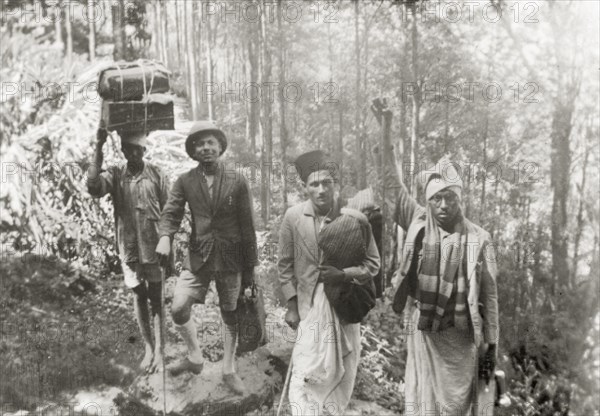 Evangelists trekking through forest, India. Methodist evangelists and Indian porters trek through a forest in the Baba Budan Giri mountain range near Pandaravalli. The group were travelling to a remote coffee estate to show a display of magic lantern slides to the plantation workers. Mysore State (Karnataka), India, 1937., Karnataka, India, Southern Asia, Asia.