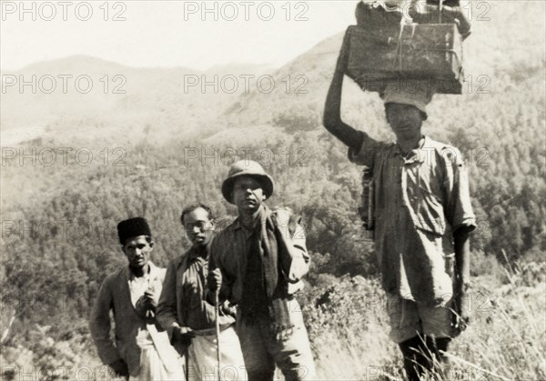 Evangelists trekking through mountain range. Methodist evangelists and Indian porters trek through the Baba Budan Giri mountain range near Pandaravalli. The group were travelling to a remote coffee estate to show a display of magic lantern slides to the plantation workers. Mysore State (Karnataka), India, 1937. India, Southern Asia, Asia.