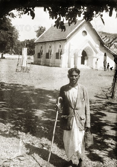 A Methodist evangelist at Chikmagalur Church. Full-length portrait of Mr S. Peter, a Methodist evangelist, standing in the grounds of Chikmagalur Church, leaning on a crook and holding a bag. Chikmagalur, Mysore State (Chikkamagaluru, Karnataka), India, circa 1937., Karnataka, India, Southern Asia, Asia.