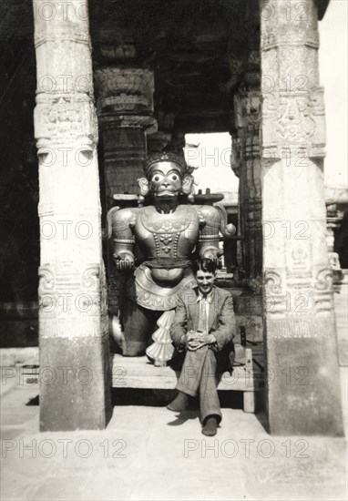 British Reverend visiting Chennakesava Temple. Reverend Norman Sargant poses beside a sculpture of a Hindu deity between the ornately carved pillars of the 'mandapa' (outdoor hall) at Chennakesava Temple, a 12th century Vaishnava temple built by King Vishnuvardhana of the Hoysala dynasty. Belur, Mysore State (Karnataka), India, circa 1937., Karnataka, India, Southern Asia, Asia.