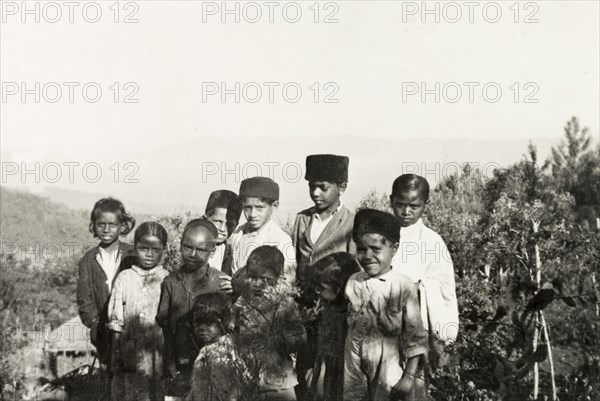 Students of a mission school, Mysore State. Students of Pandaravalli School pose for an infomal portrait by a thicket of cultivated coffee plants. The school was founded by Methodist missionaries to educate the children of plantation workers at Pandaravalli coffee estate. Mysore State (Karnataka), India, circa 1937., Karnataka, India, Southern Asia, Asia.