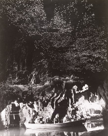 Glow-worm Grotto' at Waitomo Caves. A small tourist boat glides across the still waters of the 'Glow-worm Grotto' at Waitomo Caves, which is illuminated by thousands of insects (the fungus gnat Arachnocampa luminosa). Waitomo Caves, Waikato, New Zealand, 1966., Waikato, New Zealand, New Zealand, Oceania.