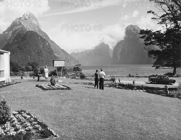 Milford Sound from the Milford Hotel. A couple admire the view of Milford Sound from the lawn of the Milford Hotel. Southland, New Zealand, 1966., Southland, New Zealand, New Zealand, Oceania.