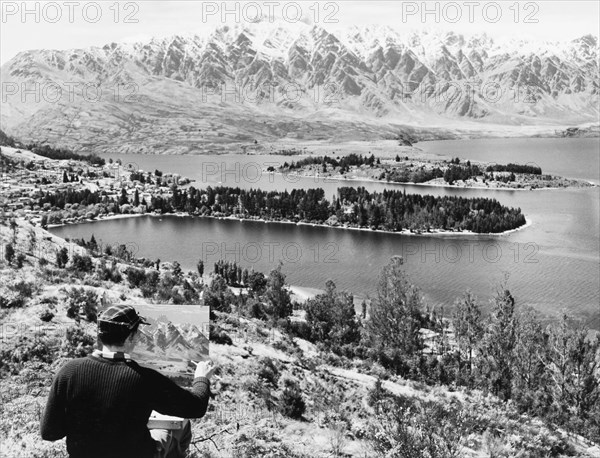Painting Lake Wakatipu and the Remarkables. An artist puts the finishing touches to a painting of Lake Wakatipu and the Remarkables Range from the mountainside of Ben Lomond. Queenstown, Otago, New Zealand, 1966., Otago, New Zealand, New Zealand, Oceania.