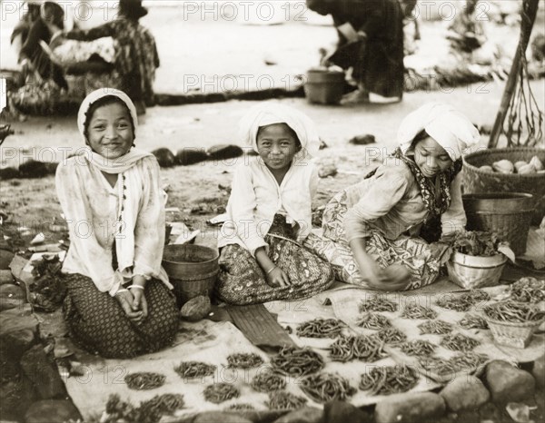 Girls selling chilli peppers in Bali. Three young Balinese girls sell chilli peppers at a village market. Bali, Indonesia, July 1940., Lesser Sunda Islands (including Bali), Indonesia, South East Asia, Asia.