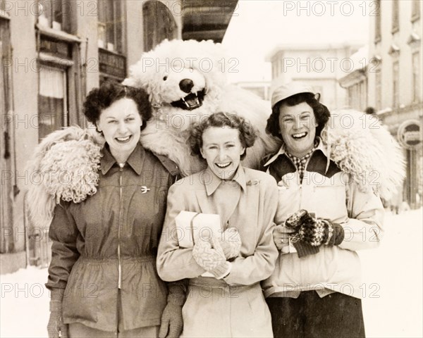 Posing with a polar bear, Switzerland. Three female tourists pose with a performer in polar bear costume during a skiing holiday in Switzerland. Davos, Switzerland, 1951. Davos, Switzerland, Switzerland, Central Europe, Europe .