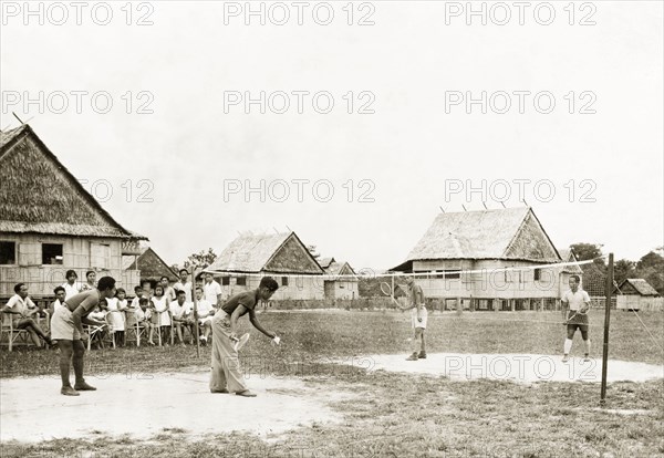 Playing badminton at Keningau Health Centre. Teachers and students at Keningau Health Centre play a game of badminton. Health officers were trained by British medical officers at the centre to introduce new hygiene and sanitation practices to local villages. Keningau, North Borneo (Sabah, Malaysia), circa 1937. Keningau, Sabah (North Borneo), Malaysia, South East Asia, Asia.