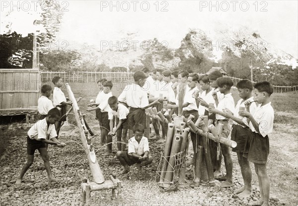 Schoolchildren washing at Keningau Health Centre. Schoolchildren wash their hands and clean their teeth using bamboo wash stands made by trainee health officers at Keningau Health Centre. An original caption notes that the toothbrushes the children use are made from coconut husks. Keningau, North Borneo (Sabah, Malaysia), circa 1937. Keningau, Sabah (North Borneo), Malaysia, South East Asia, Asia.