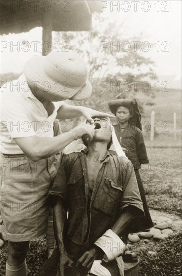 Dental treatment at Keningau Health Centre. A man receives dental treatment from a British medical officer at Keningau Health Centre. Keningau, North Borneo (Sabah, Malaysia), circa 1937. Keningau, Sabah (North Borneo), Malaysia, South East Asia, Asia.