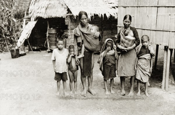 A large Malay family, North Borneo. Group portrait of a Malay family, two parents and six young children, standing barefoot outside a stilted building in a village near Keningau. Keningau, North Borneo (Sabah, Malaysia), circa 1937. Keningau, Sabah (North Borneo), Malaysia, South East Asia, Asia.