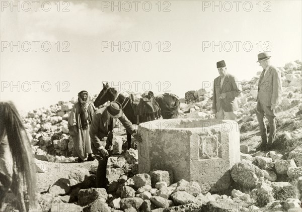 Stone well in the desert. William Ryder McGeagh, District Commissioner in Jerusalem, examines a relief carving of an eight-pointed star on a stone well in the desert. British Mandate of Palestine (Israel), circa 1940. Israel, Middle East, Asia.