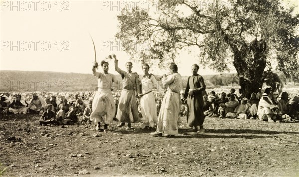 Dabke' dance at a Palestinian wedding. A group of men dressed in 'thobs' (ankle-length garments with long sleeves) perform a traditional 'dabke' folk dance at a Palestinian wedding. Salfit, British Mandate of Palestine (West Bank, Middle East), 17 September 1941. Salfit, West Bank, West Bank (Palestine), Middle East, Asia.