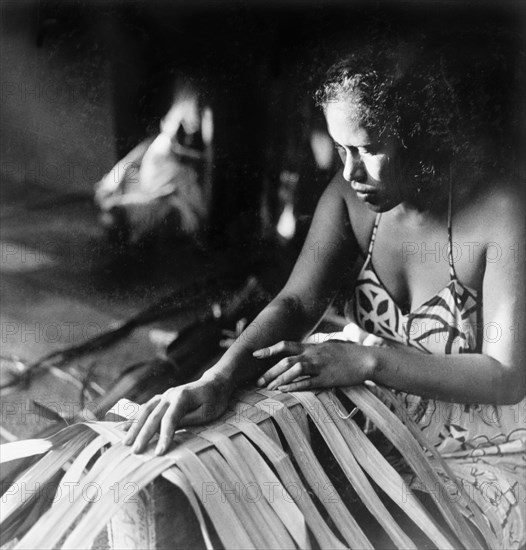 Weaving pandanus leaves. A Tahitian woman concentrates as she weaves pandunas leaves by hand. Tahiti, French Polynesia, 1965., Windward Islands (including Tahiti), French Polynesia, Pacific Ocean, Oceania.