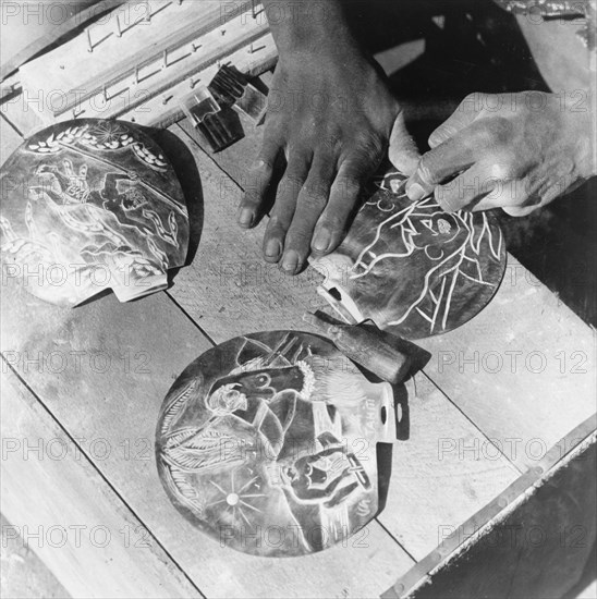 Seashells for the tourist trade. A craftsman uses a pointed tool to carve designs onto seashells destined for the tourist trade. Tahiti, French Polynesia, 1965., Windward Islands (including Tahiti), French Polynesia, Pacific Ocean, Oceania.